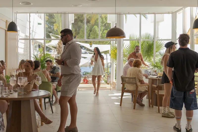 Salon interior de Tardeo by Origen lleno de gente, con los ventanales abiertos a la terraza